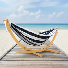 Load image into Gallery viewer, Harbour navy and white striped double cotton hammock on a solid pine arc stand beside the beach
