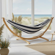 Load image into Gallery viewer, Harbour double cotton hammock with pine arc stand in a bright room overlooking the ocean
