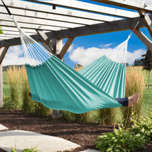 Load image into Gallery viewer, Person relaxing in a turquoise Aruba double Sunbrella hammock beneath a garden pergola