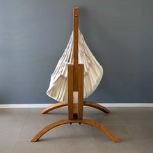 Load image into Gallery viewer, Side view of the Coastal Lounger timber stand and cream hanging chair, showing the wide curved support feet