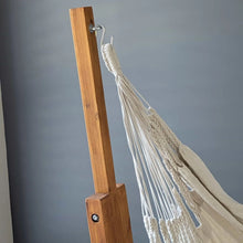 Load image into Gallery viewer, Close-up of the cream chair’s suspension loop attached to an S-hook on the timber stand