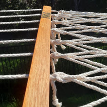 Load image into Gallery viewer, Close-up of the rope hammock’s hardwood spreader bar with cream suspension cords and knotted rope