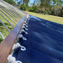 Load image into Gallery viewer, Close-up of the navy quilted hammock bed, wooden spreader bar, metal eyelets and white suspension cords