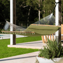 Load image into Gallery viewer, Olive Whitsunday King Quilted Hammock with matching pillow suspended between patio posts beside a garden