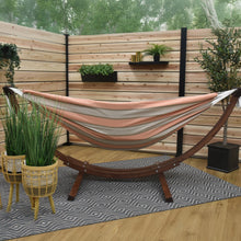 Load image into Gallery viewer, Cameo striped hammock on a solid pine arc stand in a timber-screened space with potted plants.