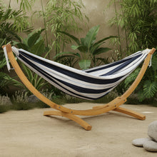 Load image into Gallery viewer, Harbour striped double cotton hammock on a pine arc stand surrounded by tropical plants