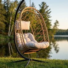 Load image into Gallery viewer, Cappuccino Deluxe Nest Chair showing its cushioned seat and pillow beside a lake in warm sunlight.