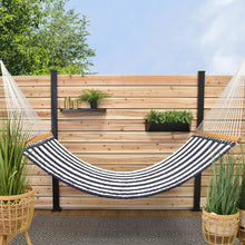 Load image into Gallery viewer, Harbour navy and white striped quilted hammock with wooden spreader bars, hanging in front of a timber privacy screen.